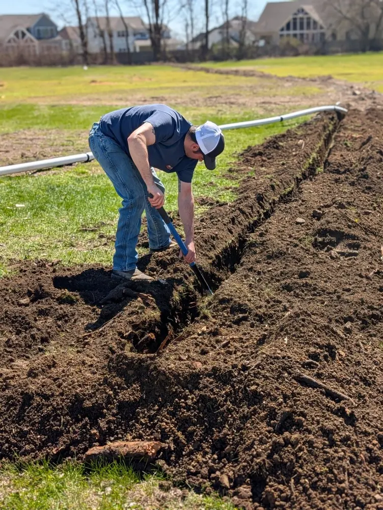 Operator trenching a straight utility run through a residential lawn