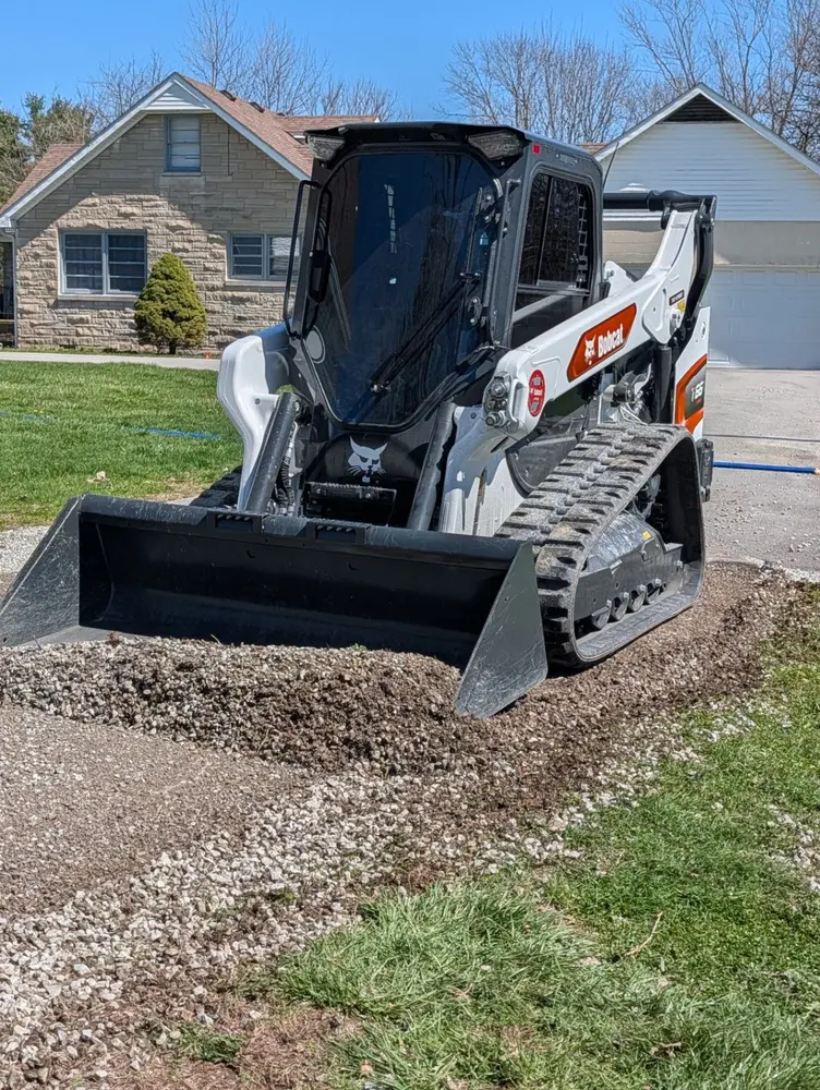 Bobcat loader with a rotary brush attachment working across open land