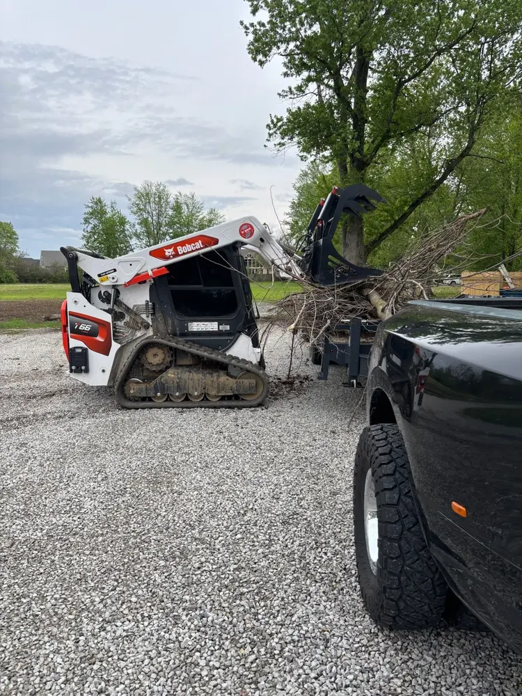 Bobcat loader working across a sloped grassy property